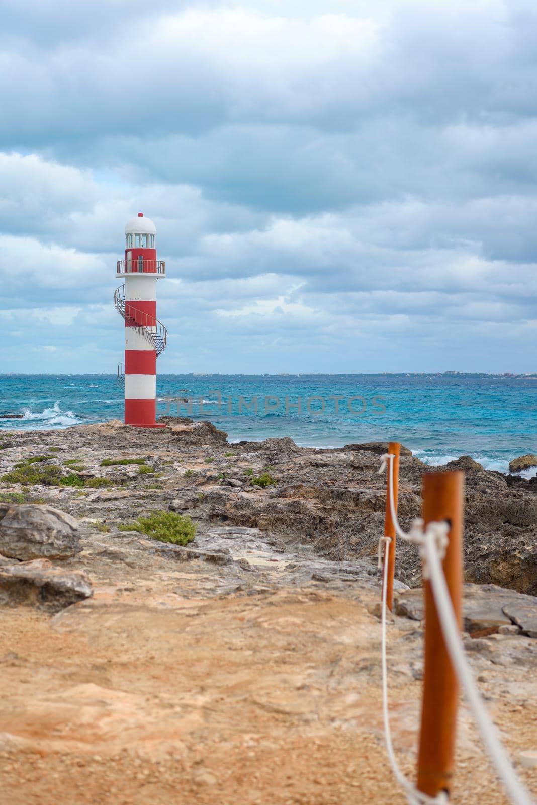 Lighthouse on a rocky shore in Cancun. Clear sky and blue sea.