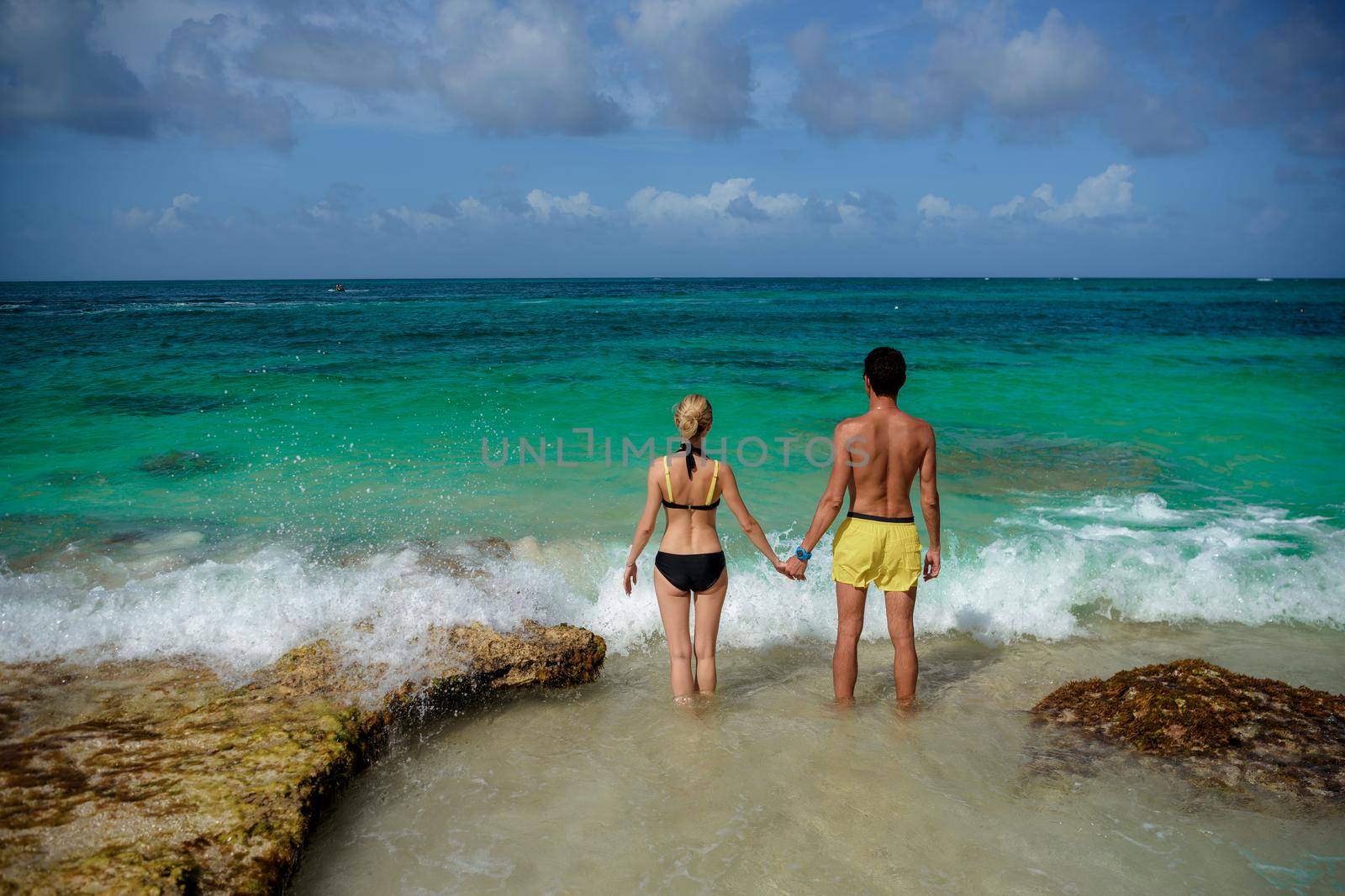 A man and a woman walk on the seashore.