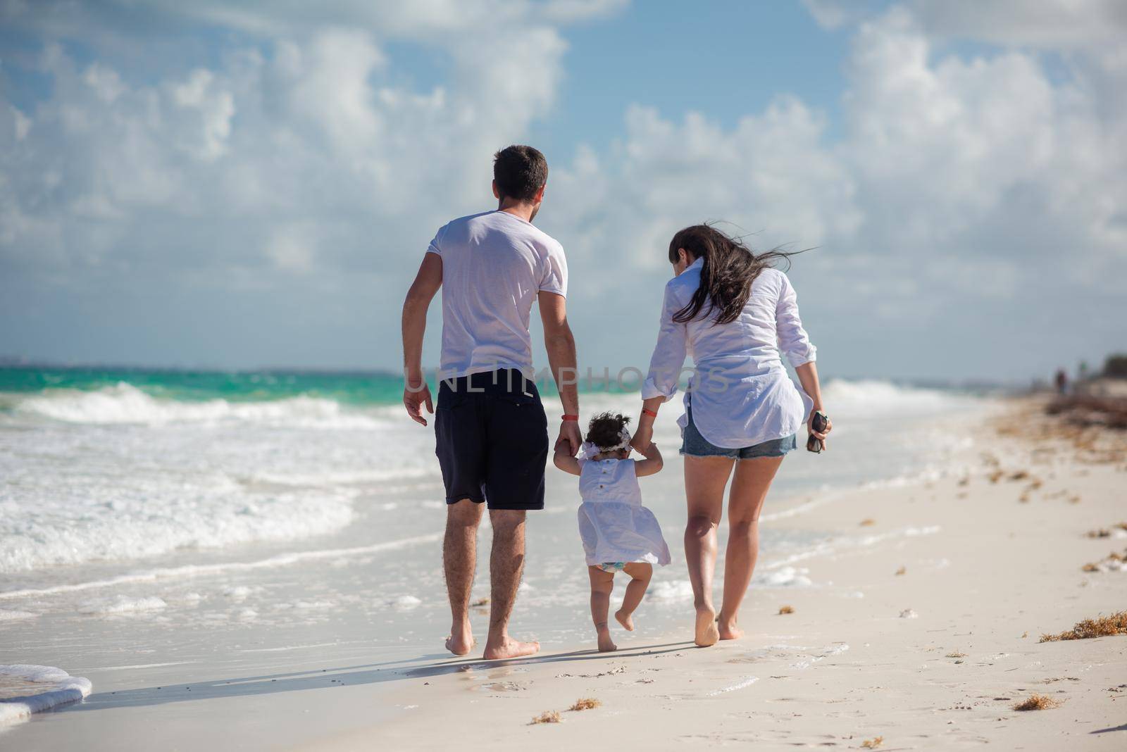 Parents with a small child walk on the beach and admire the horizon. Mexico..