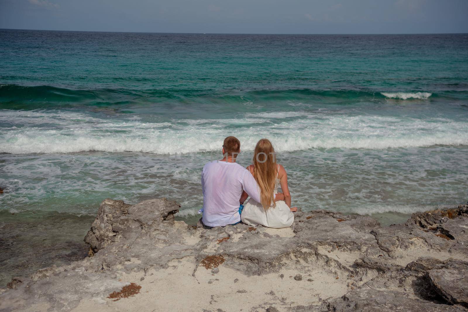 A man and a woman are sitting on the seashore.