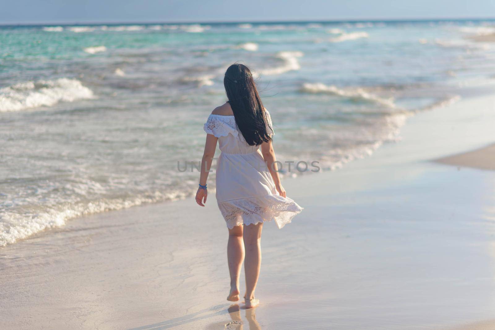 A woman on the beach looks at the horizon and walks along the beach. Mexico.