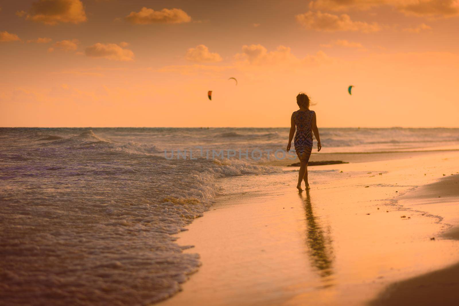 The silhouette of a woman on the beach and against the backdrop of the city sunset.