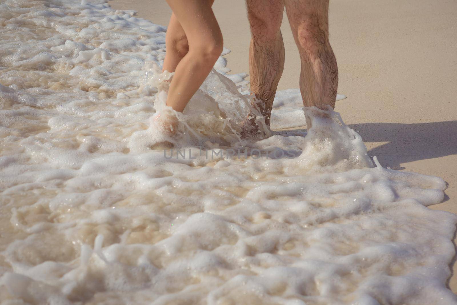 Feet of man and woman in the sand.