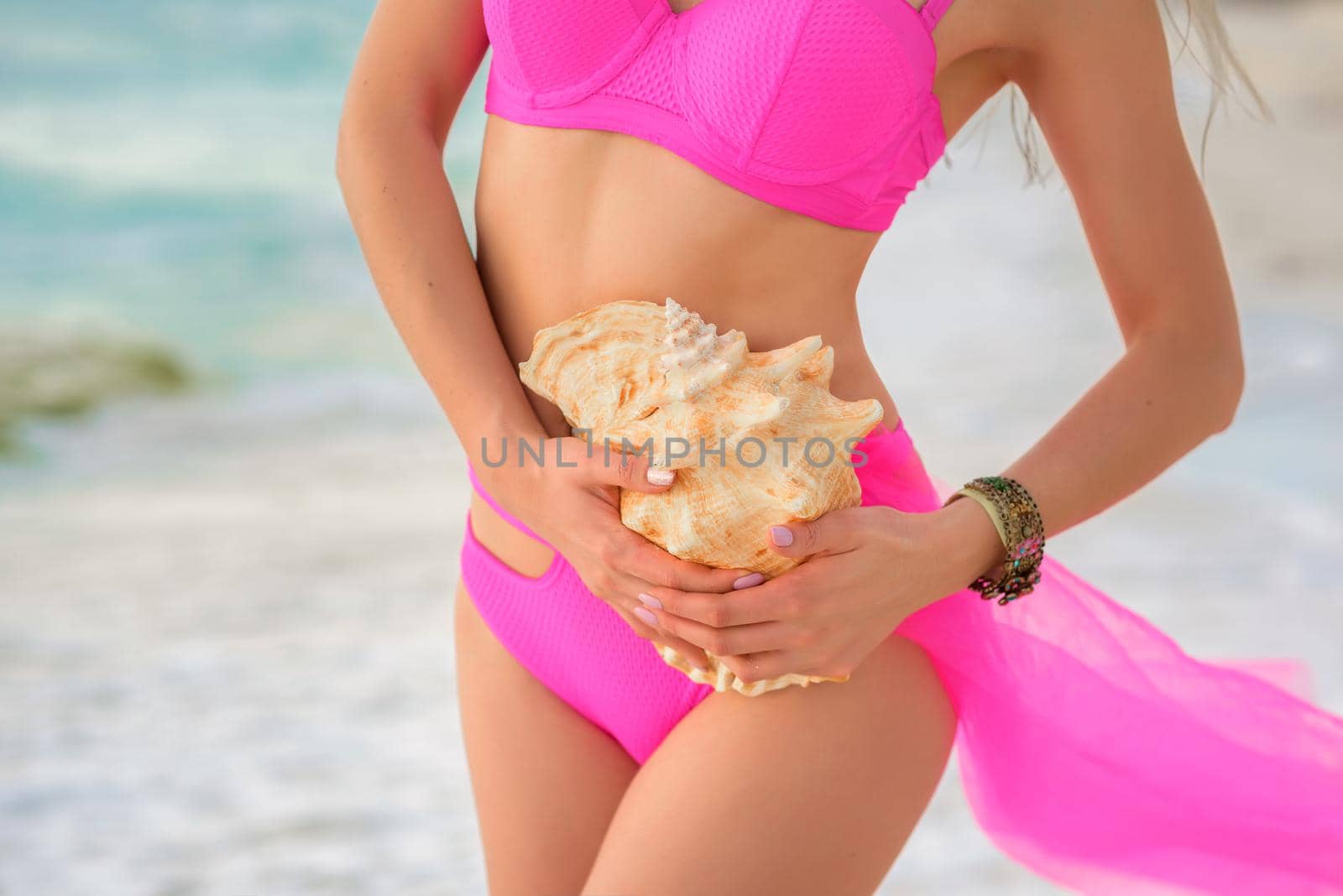 A huge shell in the hands of a girl in a dress.