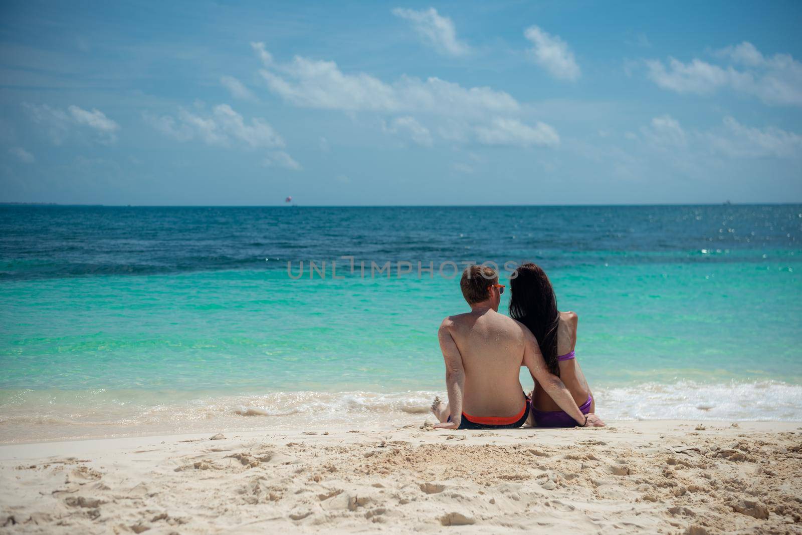 A man and a woman are sitting on the seashore.