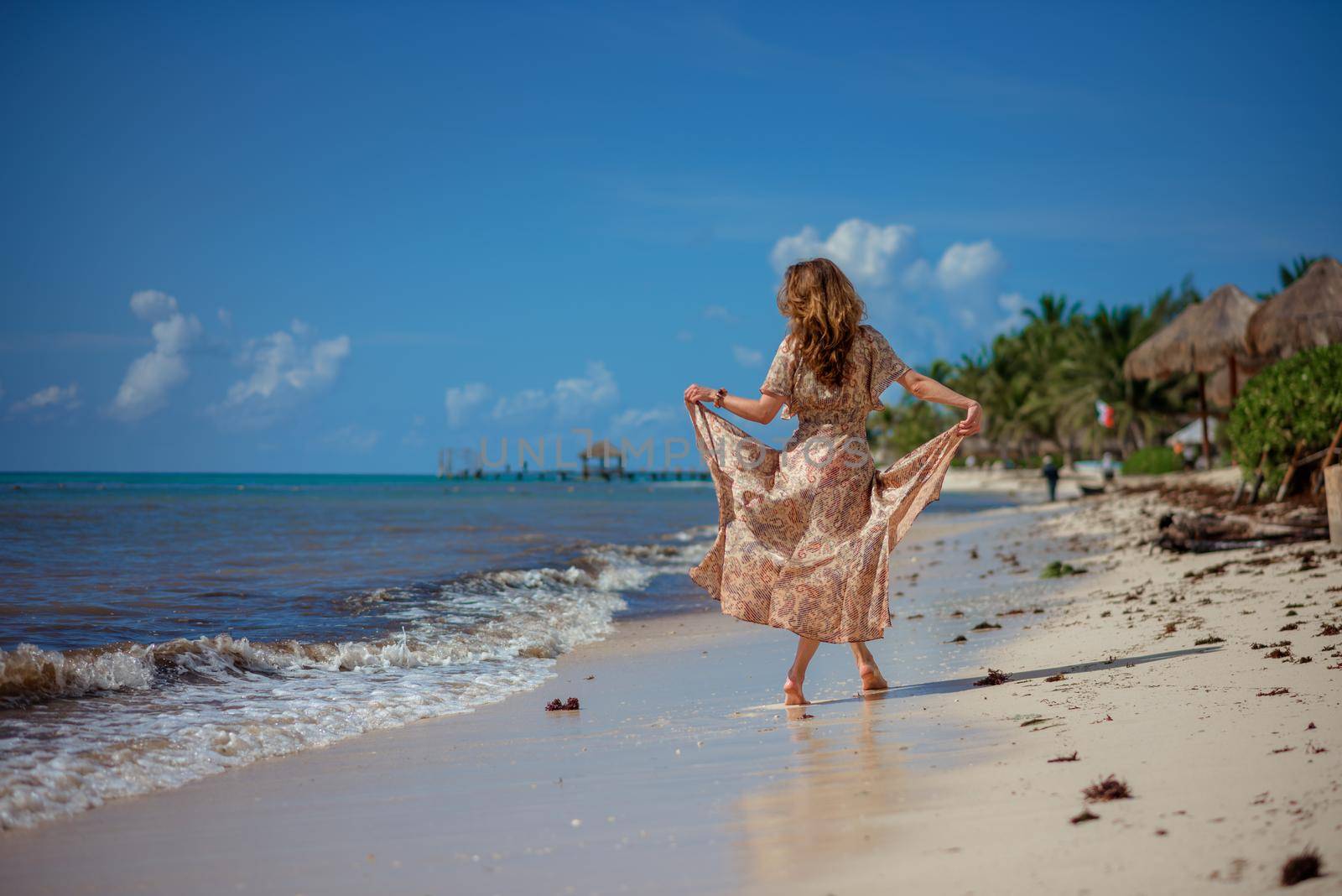 A woman on the beach looks at the horizon and walks along the beach. Mexico.