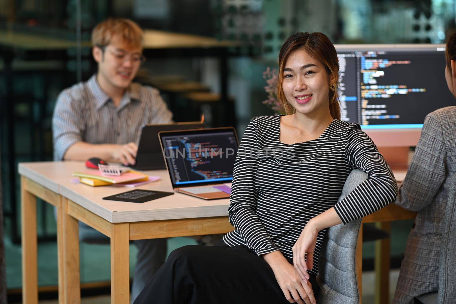 Confident young female professionals web developer sitting in software development office.