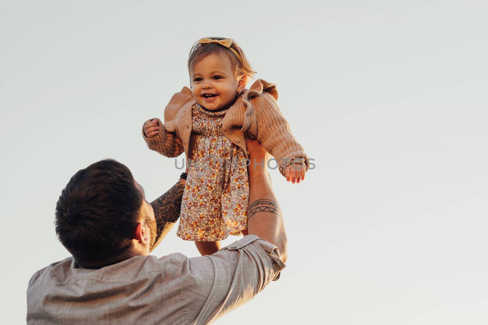 Daddy Lifting His Baby Daughter in Arms on Sky Background at Sunset, Happy Father's Day Concept