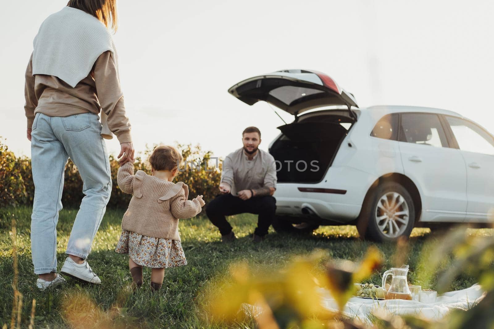 Young Family Enjoying Road Trip, Mother and Father with Little Daughter Outdoors Having Picnic with SUV Car on Background