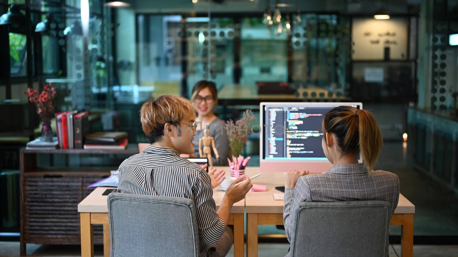 Team of young professionals brainstorming and working in software development office by prathanchorruangsak