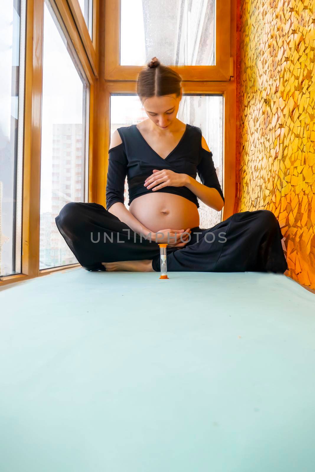 young pregnant woman hugging her belly while sitting in the lotus position. High quality photo