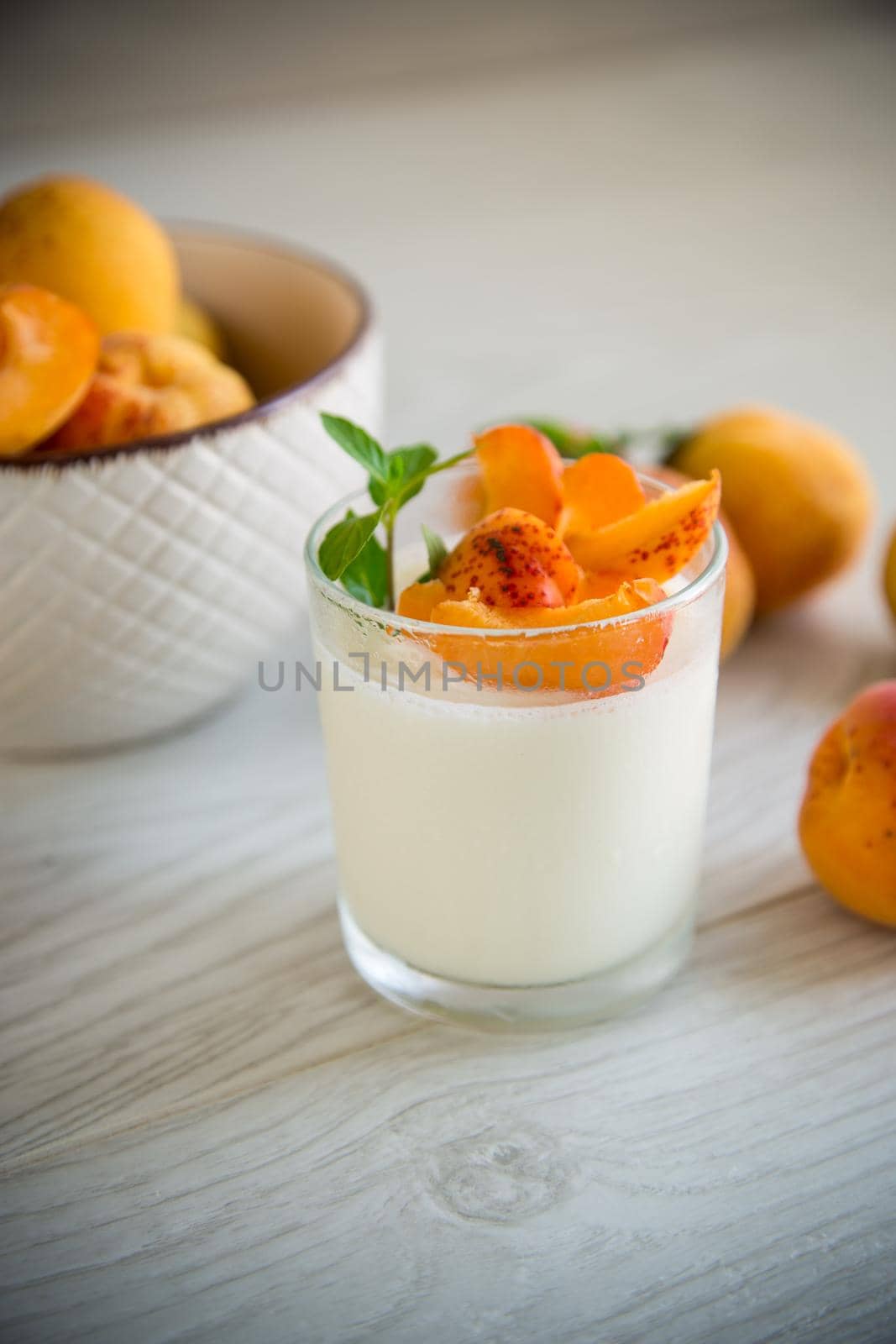 Healthy breakfast of homemade yogurt in a glass with fresh apricots on the table.