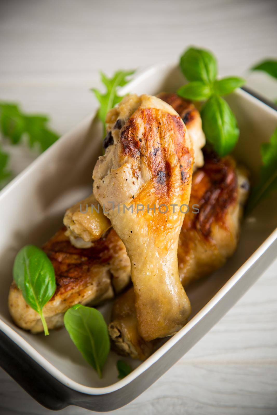 grilled chicken legs fried with spices and herbs in a ceramic bowl