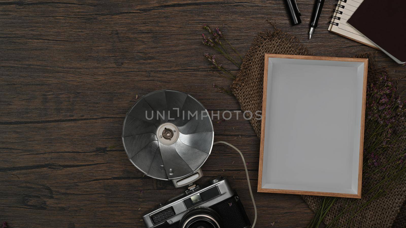 Above view retro camera, empty picture frame and notebook on wooden background by prathanchorruangsak