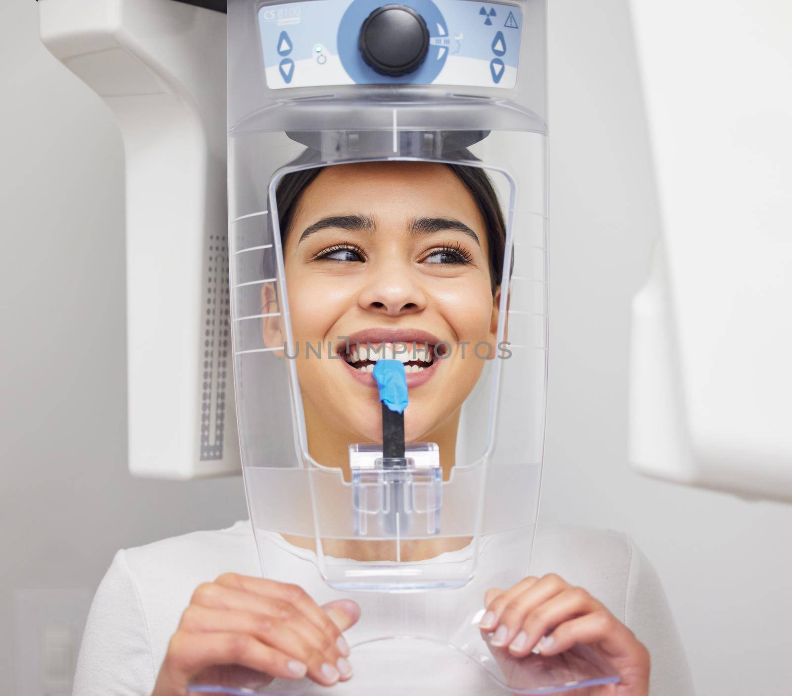 a young woman using an x ray machine at a dentists office.