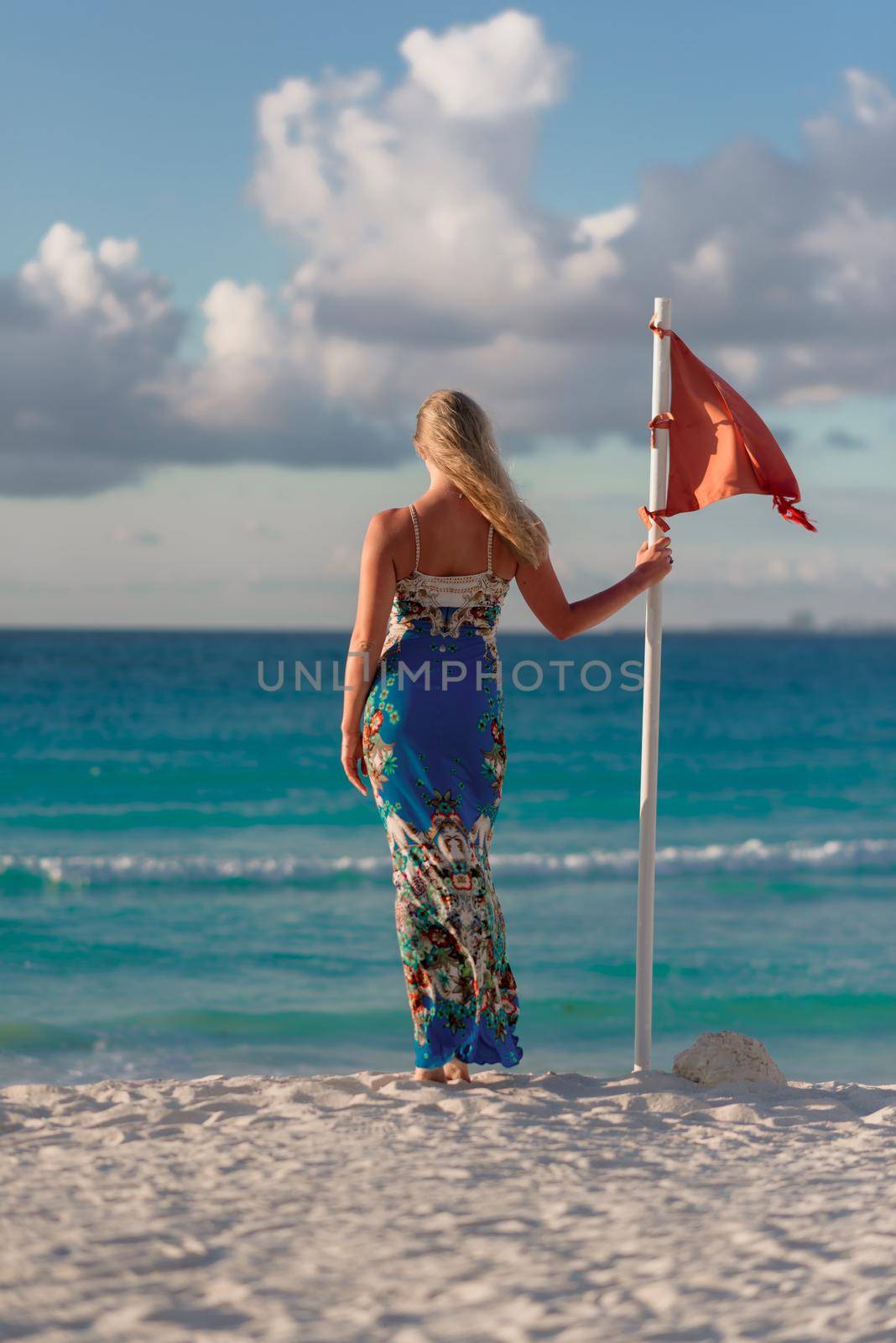 A woman stands on the beach near the red flag. Mexico.