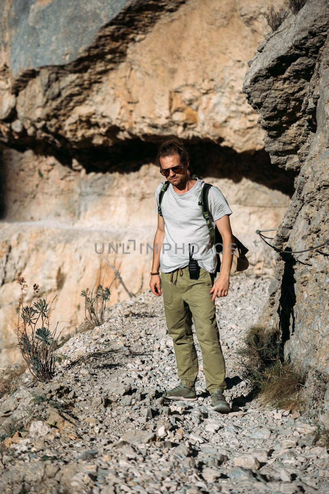 Brutal traveler man hiking in the mountains with walkie talkie outdoors on wild nature. Hiker with backpack and radio set