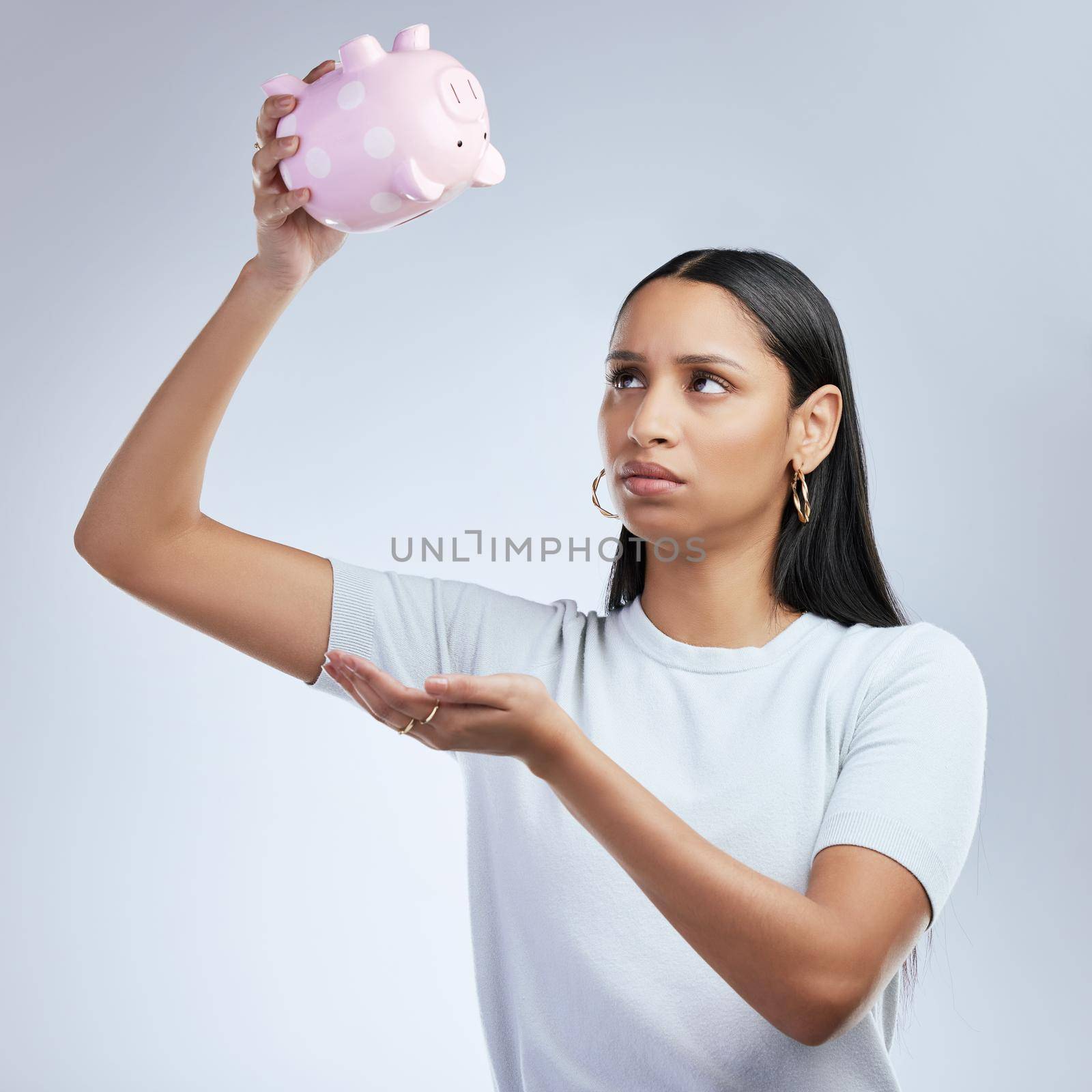 I dont have a cent. a woman holding an empty piggy bank. by YuriArcurs