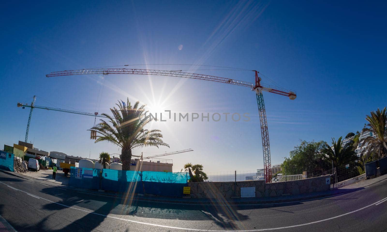 February 03 2022-Mountain top construction site in the Canary Island resort town of Puerto Rico with blue skies and a very tall crane