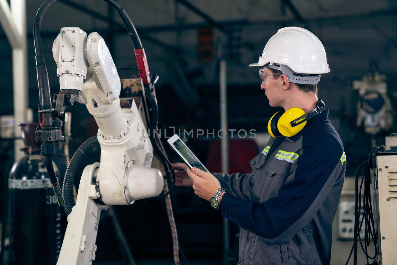 Young factory worker working with adept robotic arm in a workshop . Industry robot programming software for automated manufacturing technology .