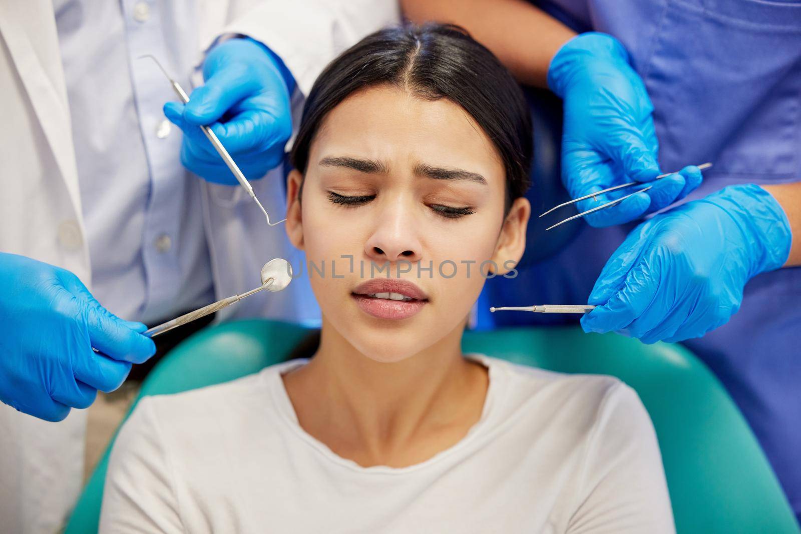Gentle care is the cure for anxiety. a young woman experiencing anxiety while having a dental procedure performed on her. by YuriArcurs