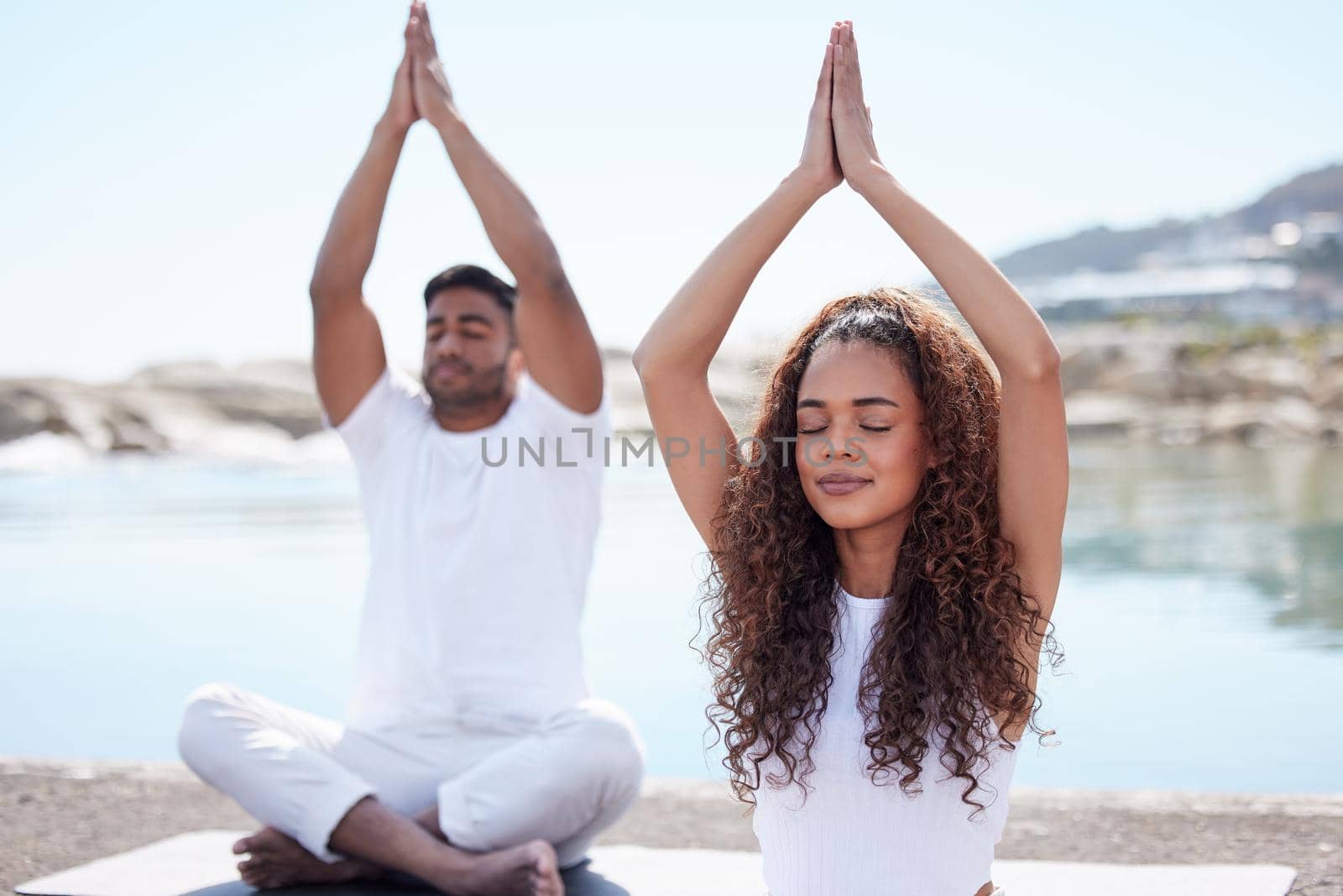a young couple practicing yoga at the beach.
