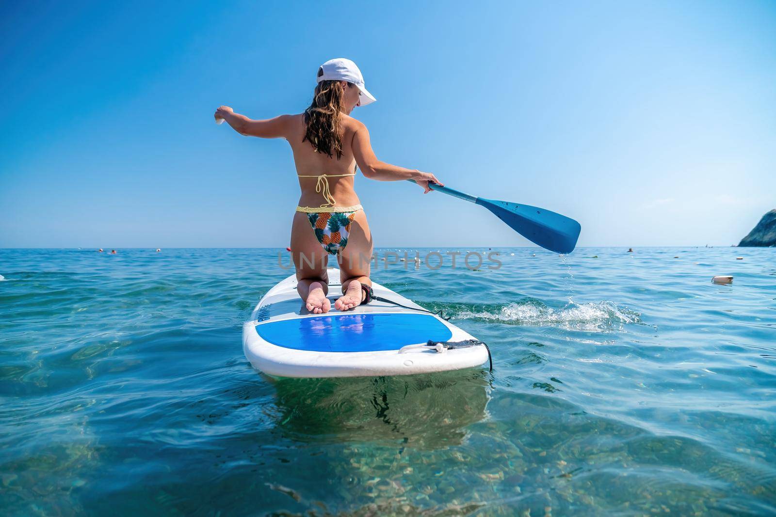 SUP Stand up paddle board. Young woman sailing on beautiful calm sea with crystal clear water. The concept of an summer holidays vacation travel, relax, active and healthy life in harmony with nature. by panophotograph