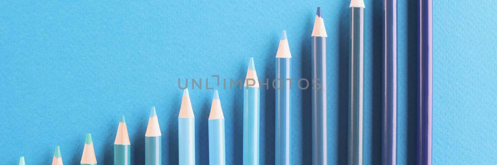 Top view of blue colored pencil set arranged in increasing way on surface and not exactly in row. Tool for draw your dreams, ideas and vision. Art concept