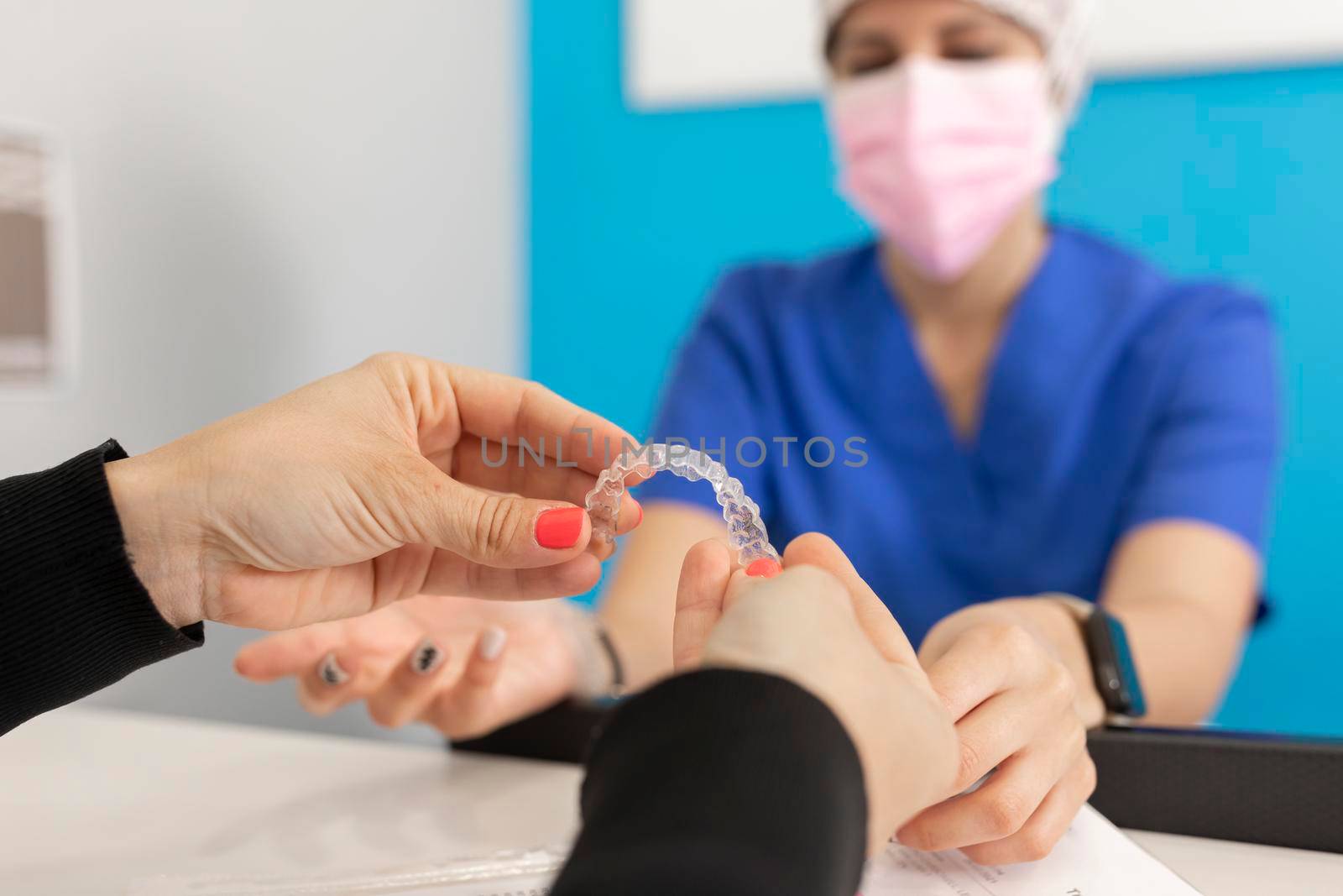 Hands holding invisible orthodontics at the dental clinic by stockrojoverdeyazul