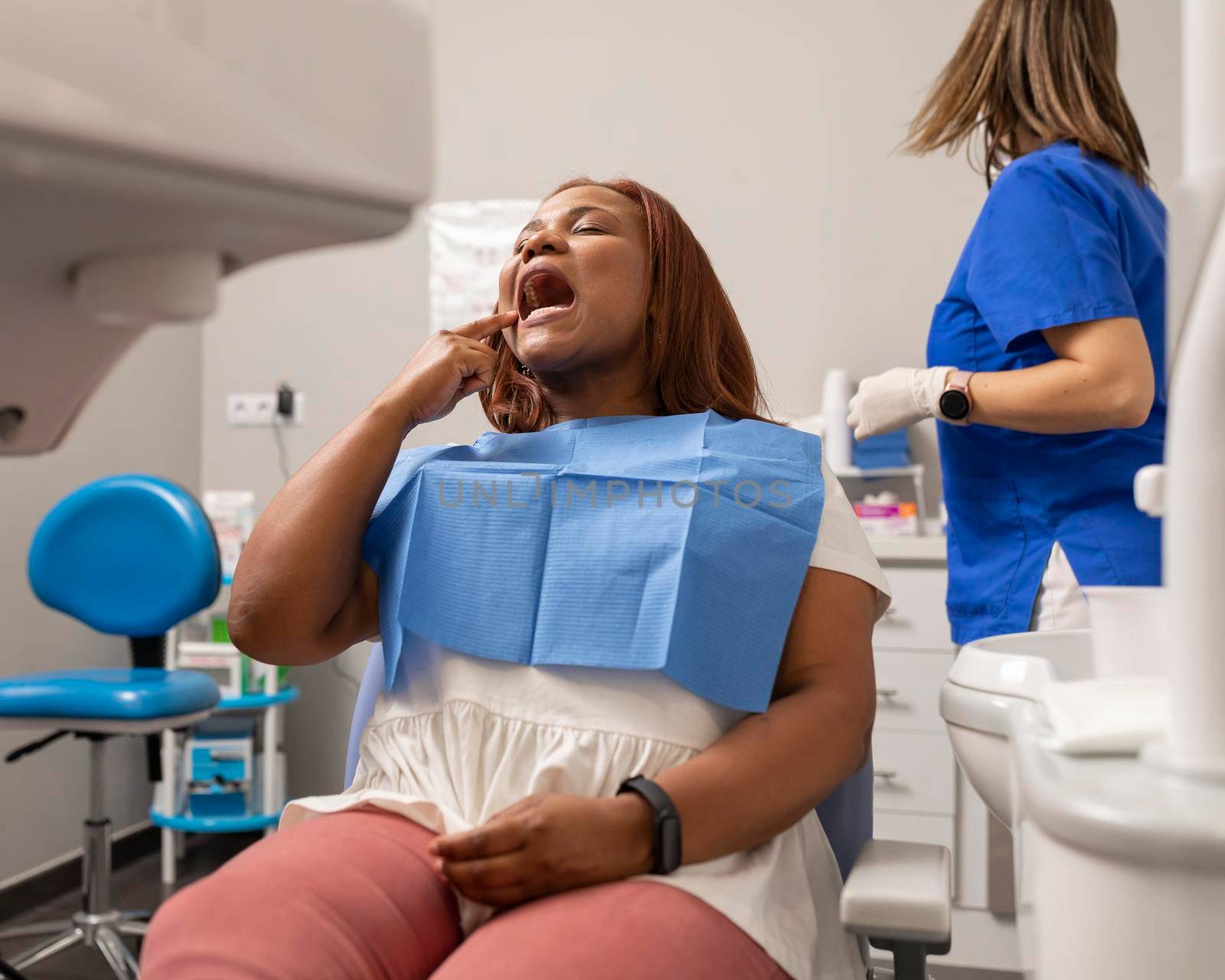 A client shows where she has the pain at the dental clinic by stockrojoverdeyazul