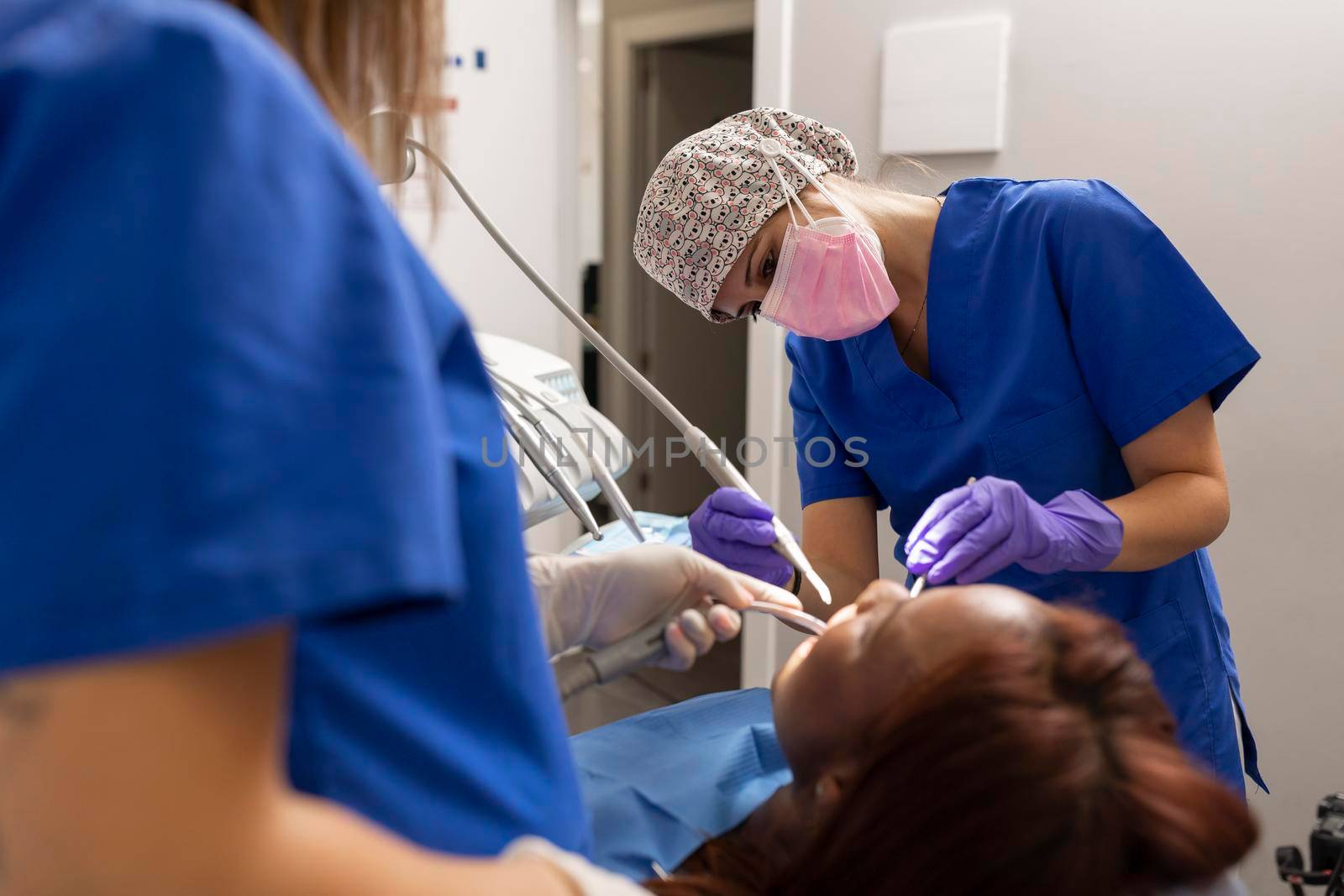 Two dentist women treating a patient at the dental clinic by stockrojoverdeyazul
