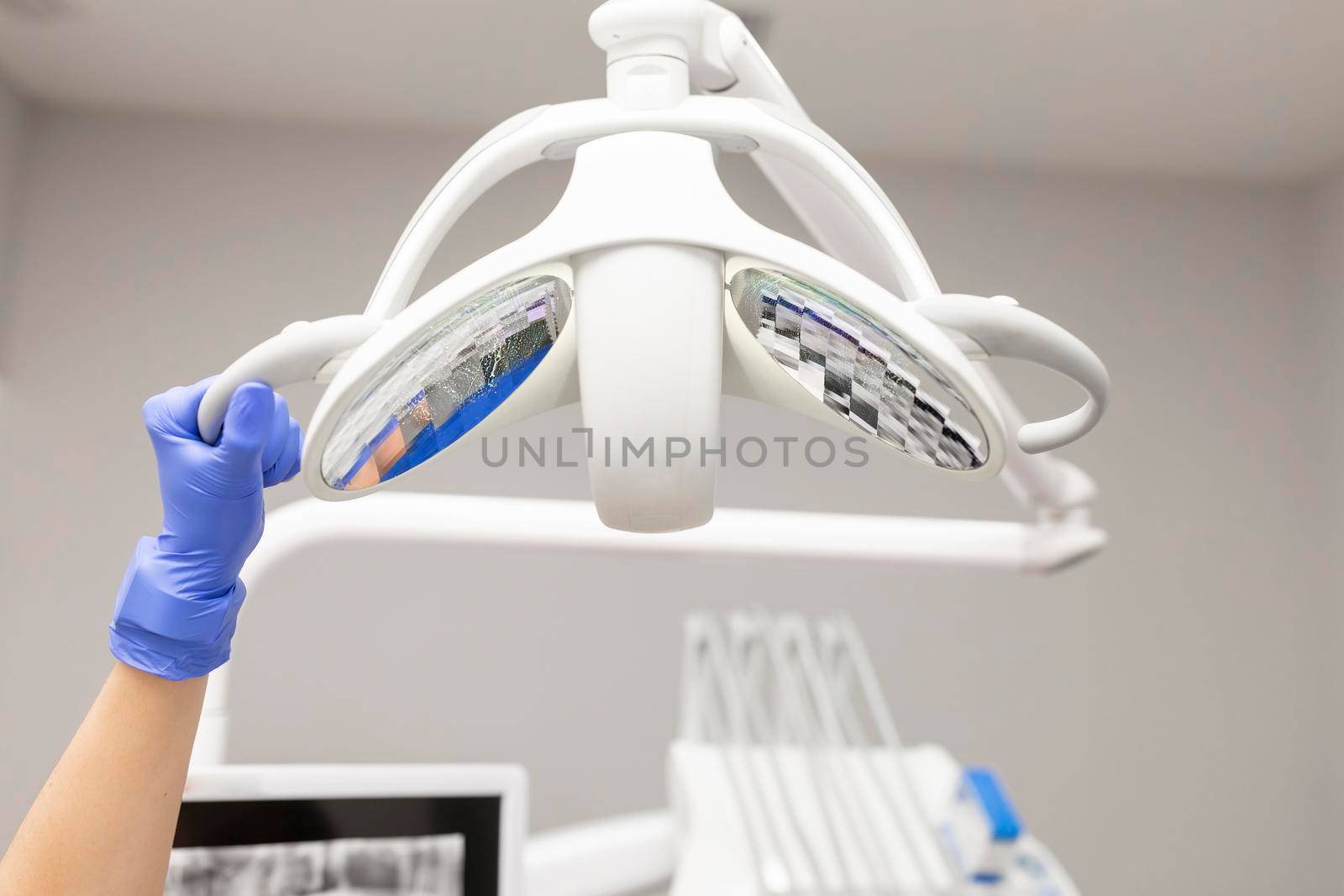 A dentist woman's hand adjusting the dental chair's light in order to properly see the issues regarding her client at the dental clinic