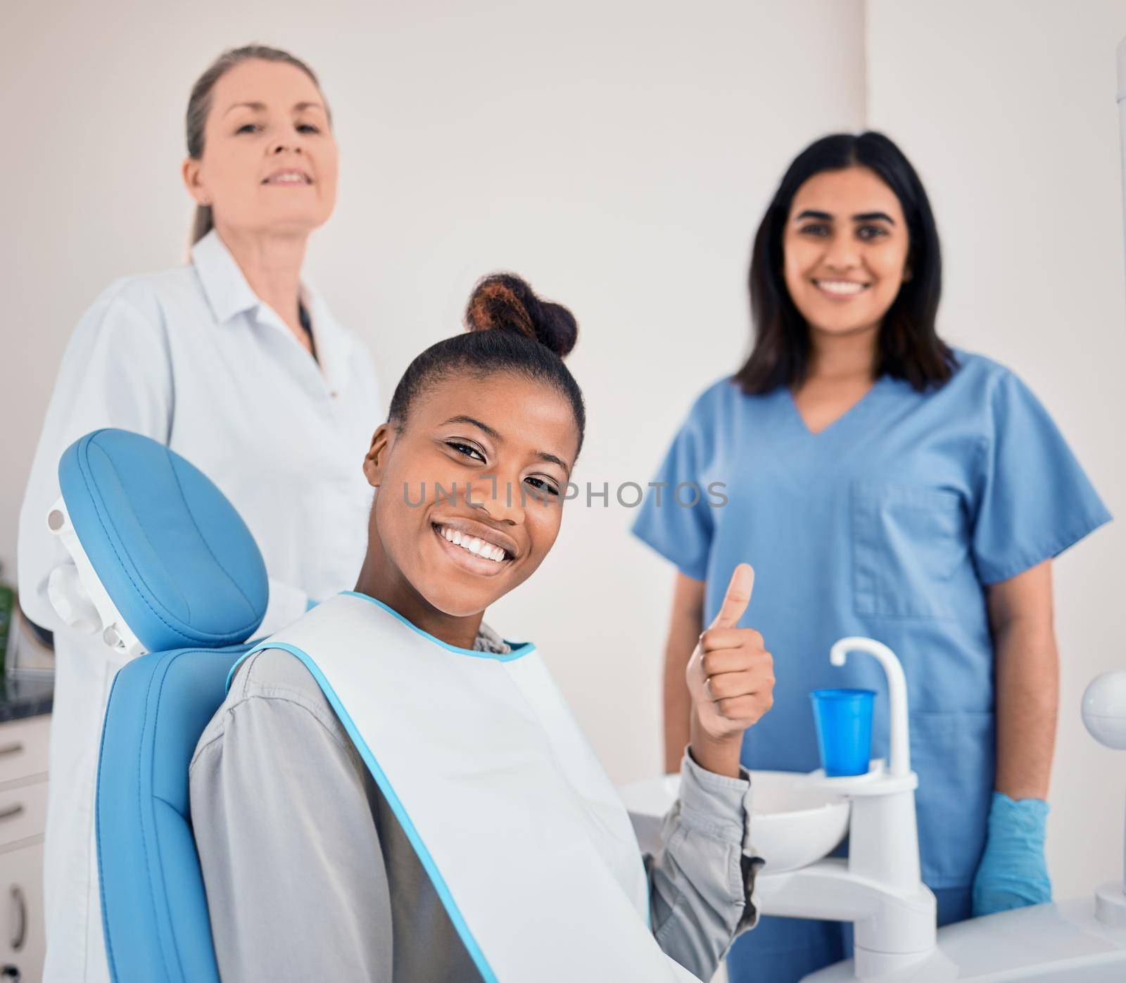 a young woman in her dentists office giving the thumbs up.