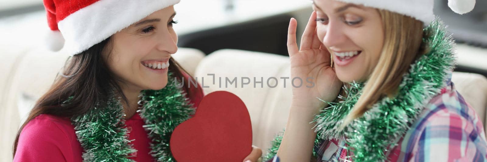 Portrait of woman got present smartphone from sister in heart shaped box. Happy woman shocked and cheerful at same time. New year, christmas, fun concept