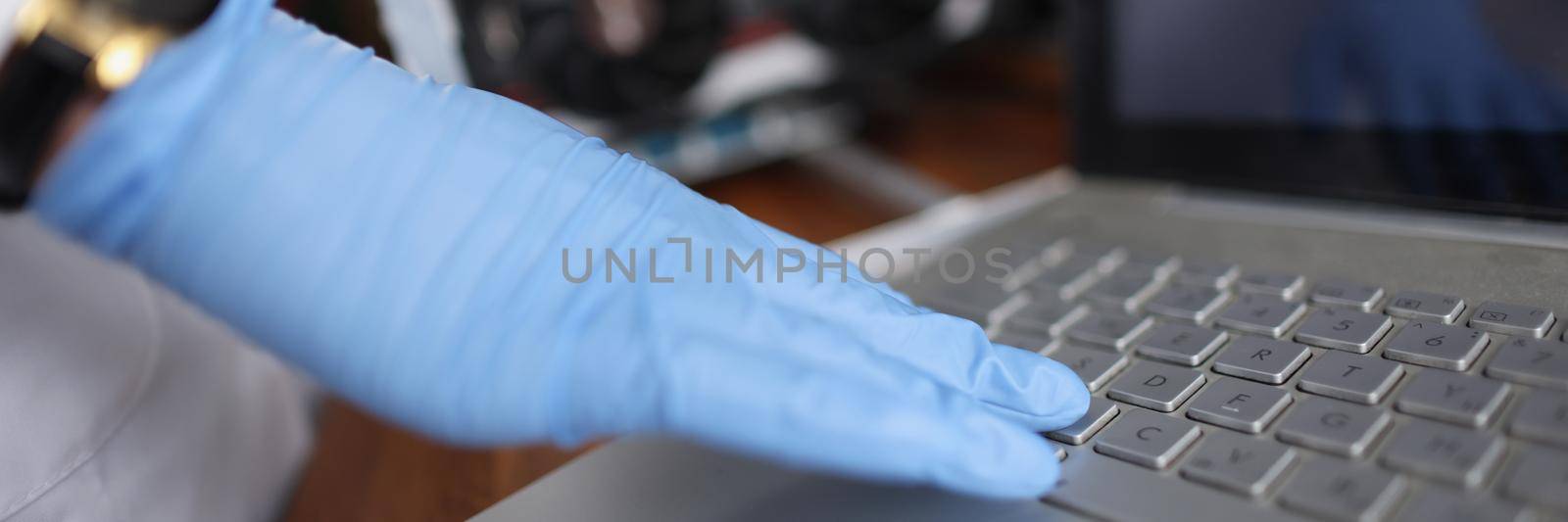 Close-up of professional technician man touching laptop keyboard wearing sterile gloves. Person check device on hidden failure. Tech maintenance concept