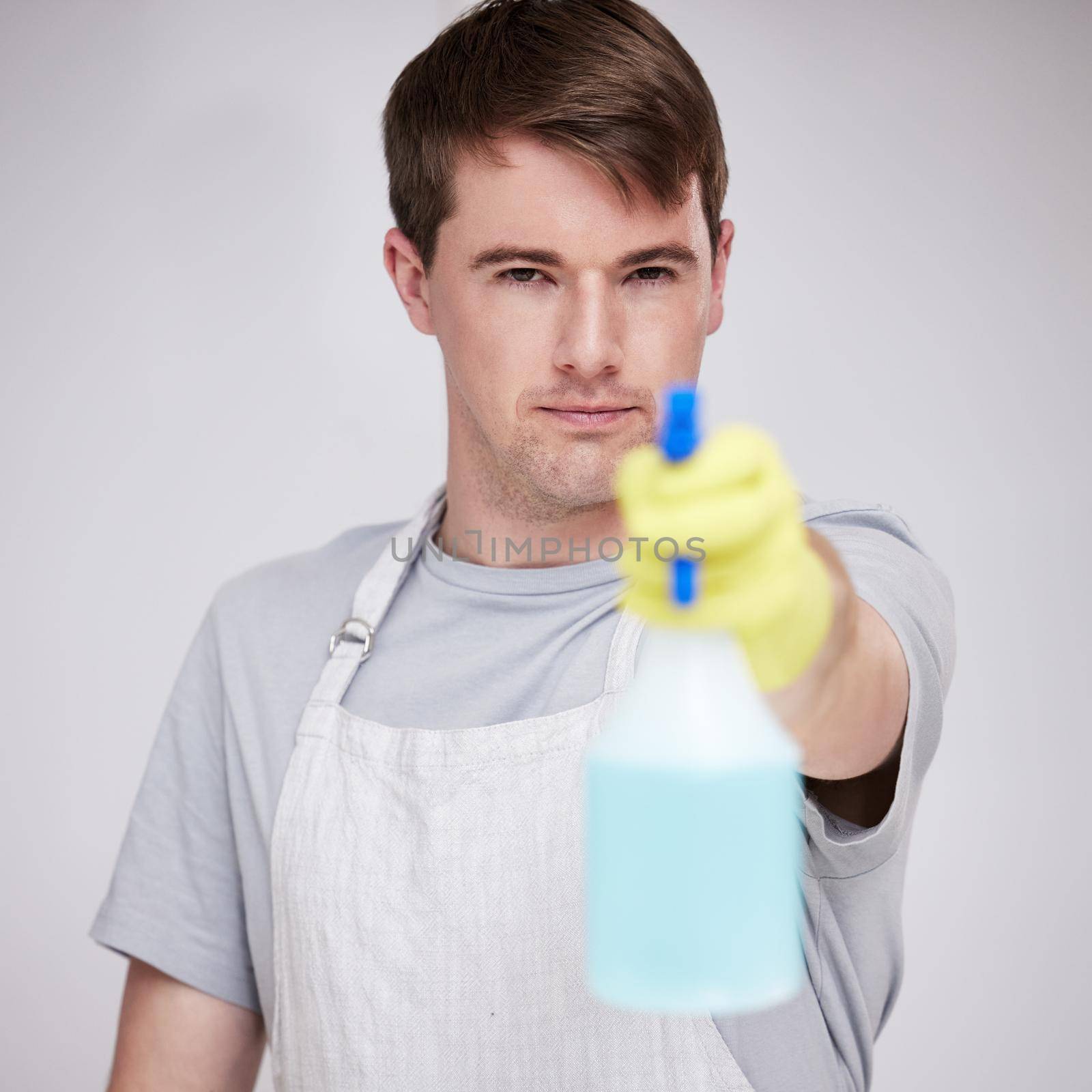 Well spray all the dirt away. a young man holding a spray bottle against a grey background. by YuriArcurs