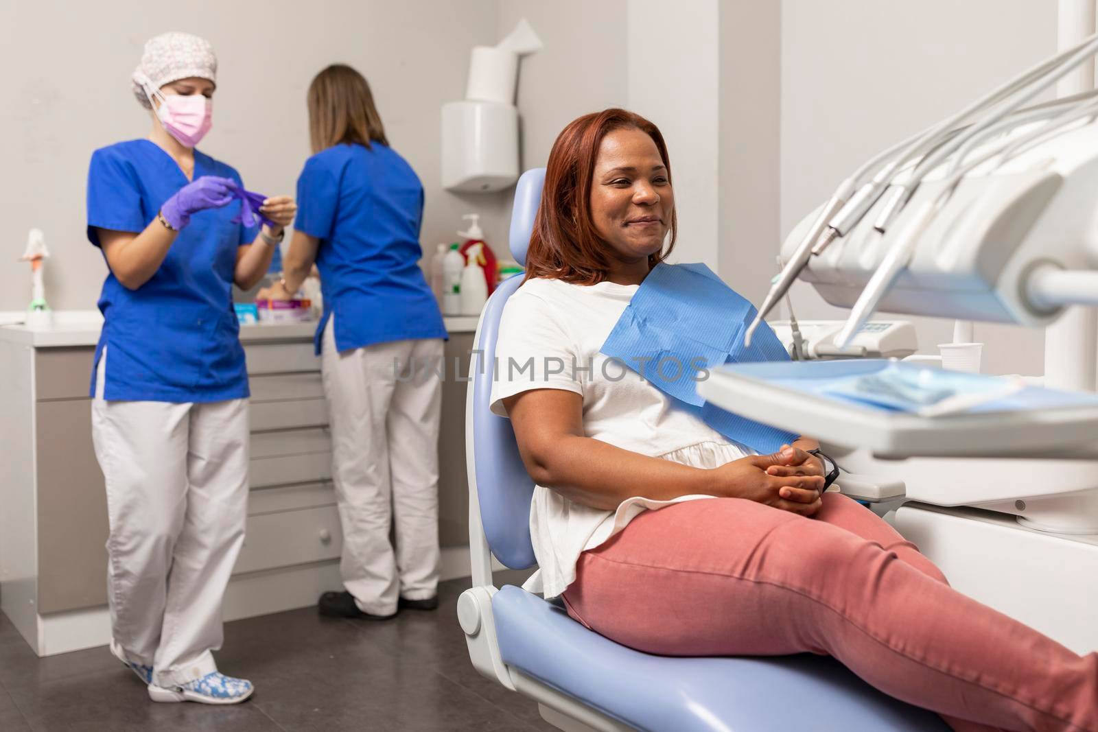 The patient waits at the dental chair for the dentist and her assistant, while they prepare the tools and equipment for the treatment at the dental clinic