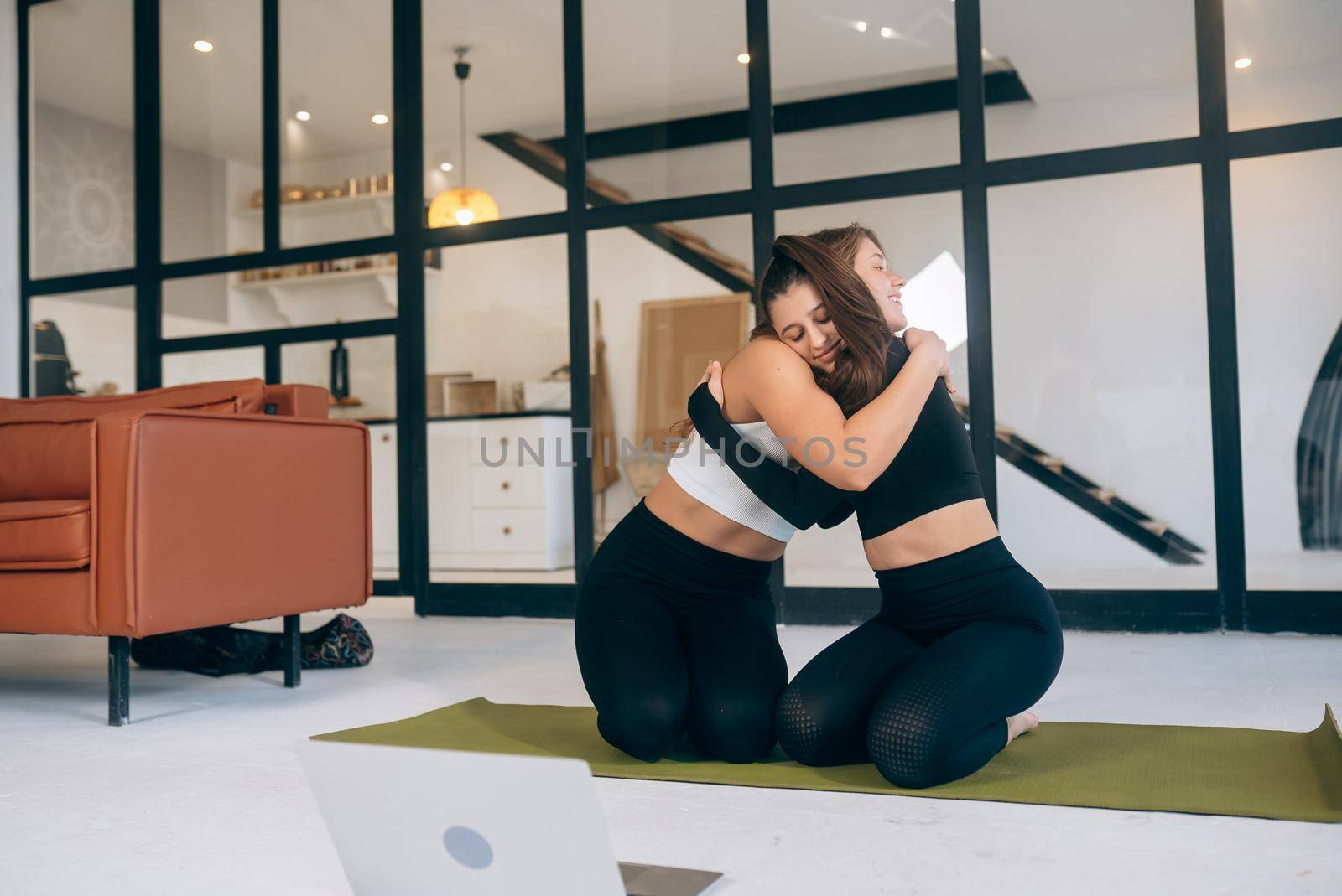 Two girlfriends hug each other after yoga at home