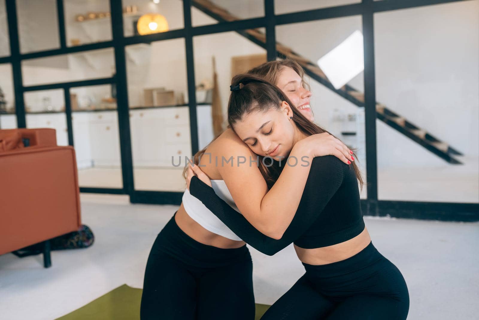 Two girlfriends hug each other after yoga by teksomolika