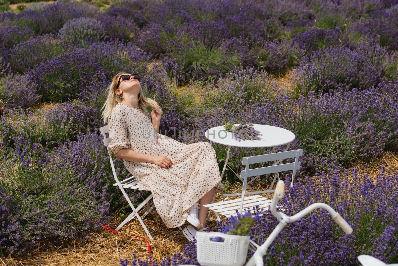 Relaxed young woman sitting in a lavender field a sunny day. by leonik