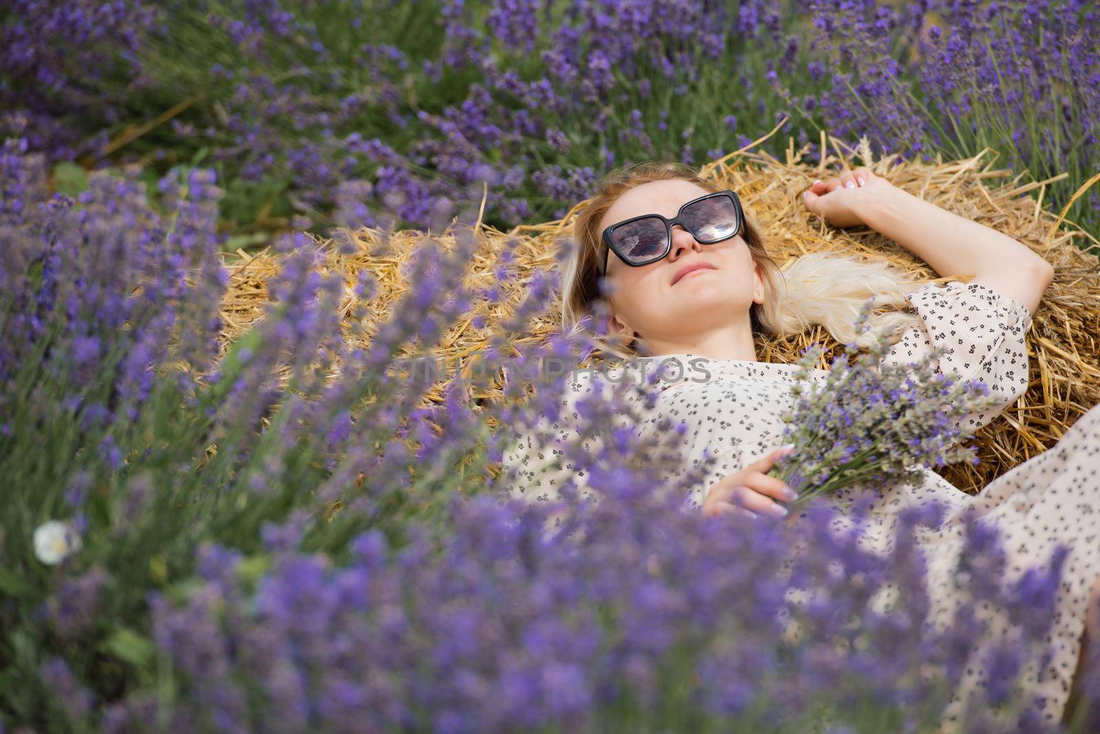 Relaxed young woman lies in a lavender field a sunny day.