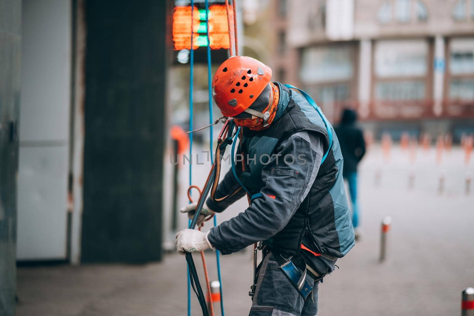 Worker climber preparing for work. Climber tightens the safety belt and check fixing and carbines