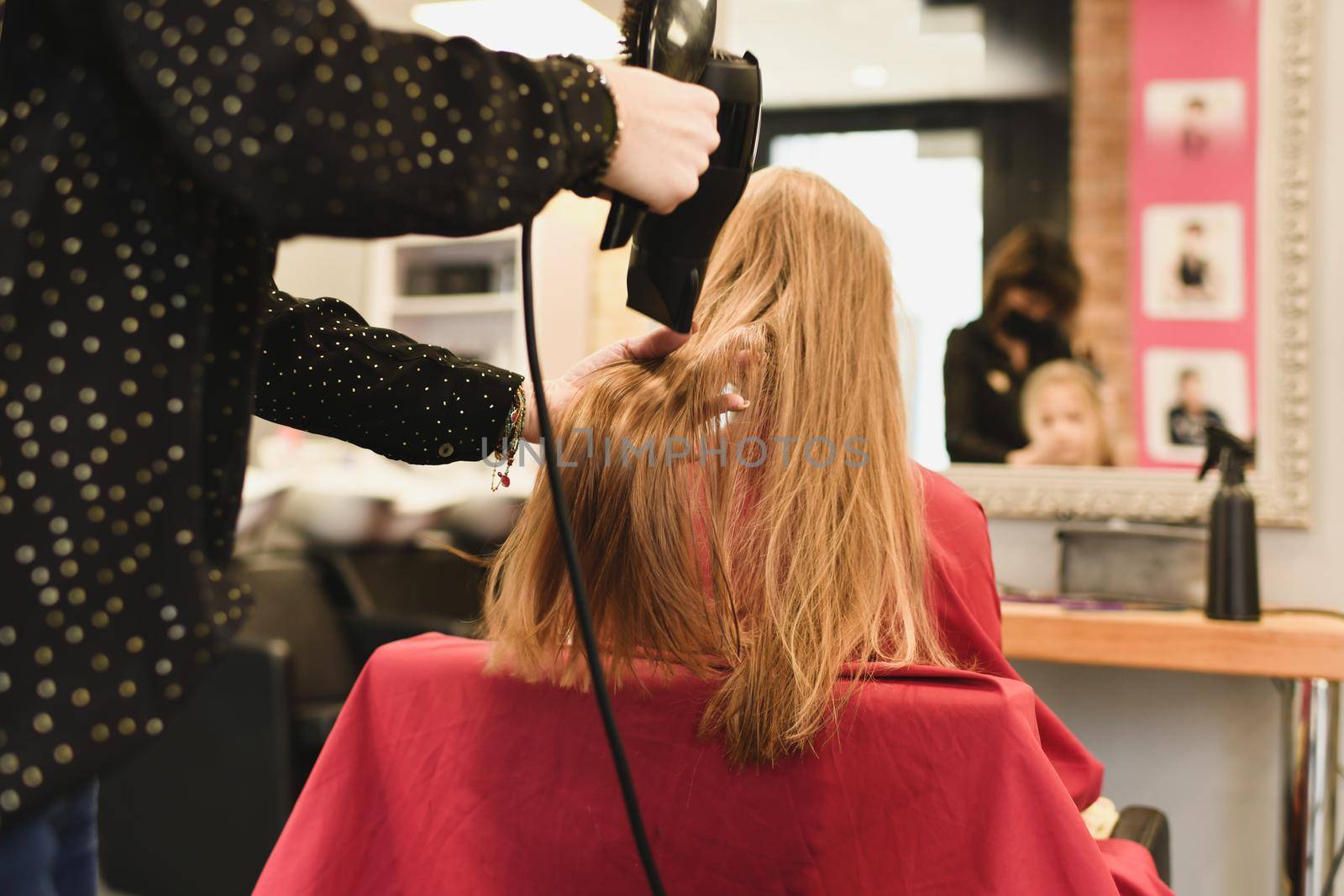 Hairdresser dries hair with a hairdryer at a saon by Godi