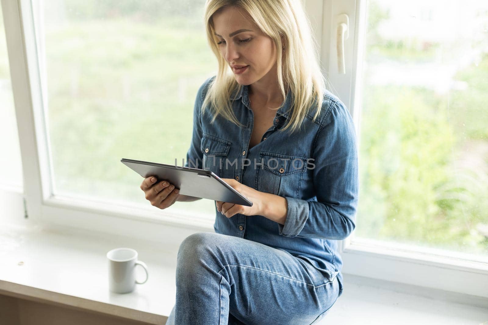 Young woman holding the tablet and sitting at home. by Andelov13