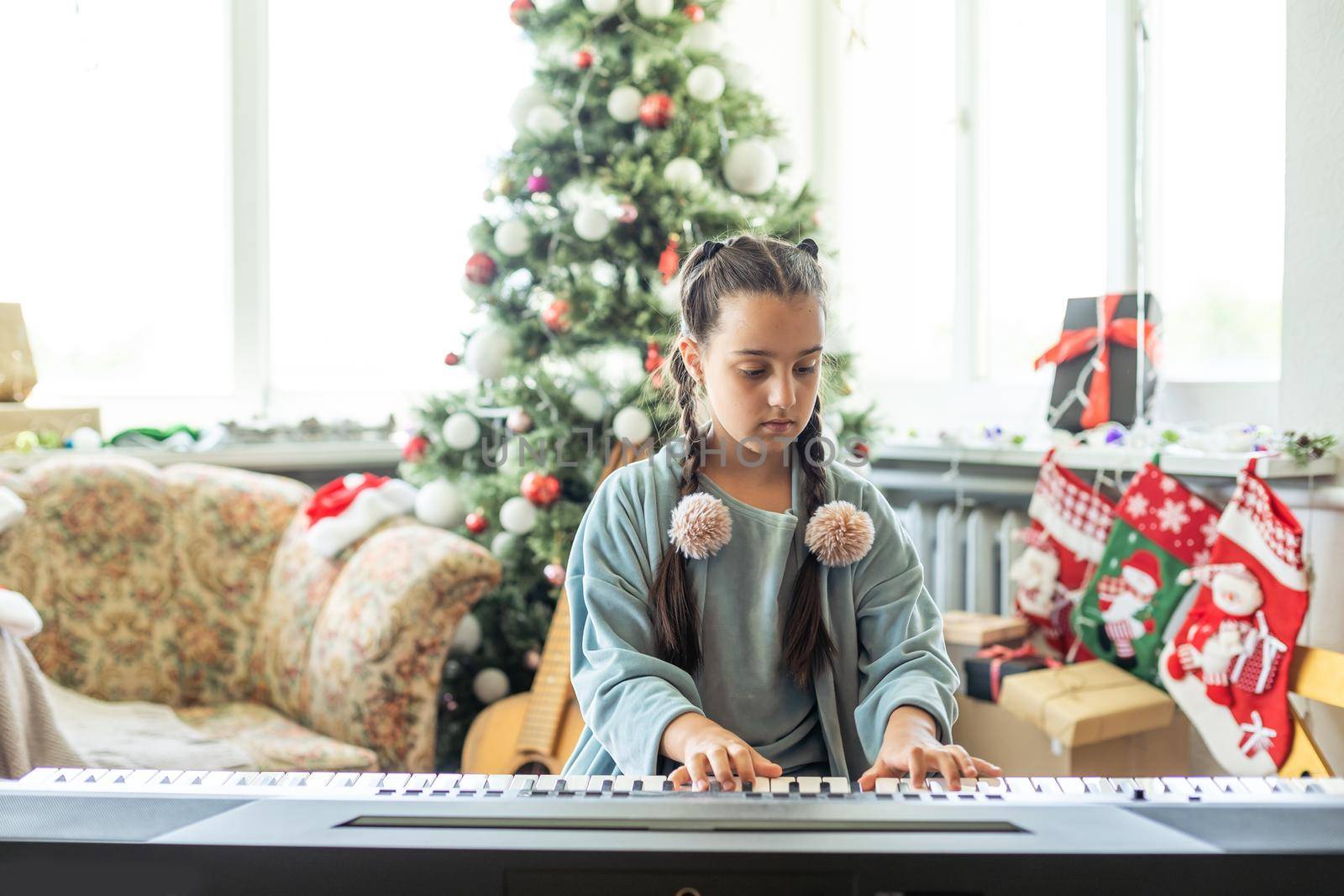 Christmas child little girl playing on piano at home by Andelov13