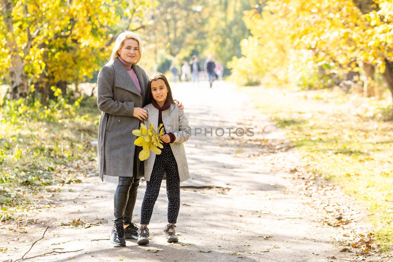 happy family: mother and child little daughter play on autumn walk in nature outdoors by Andelov13