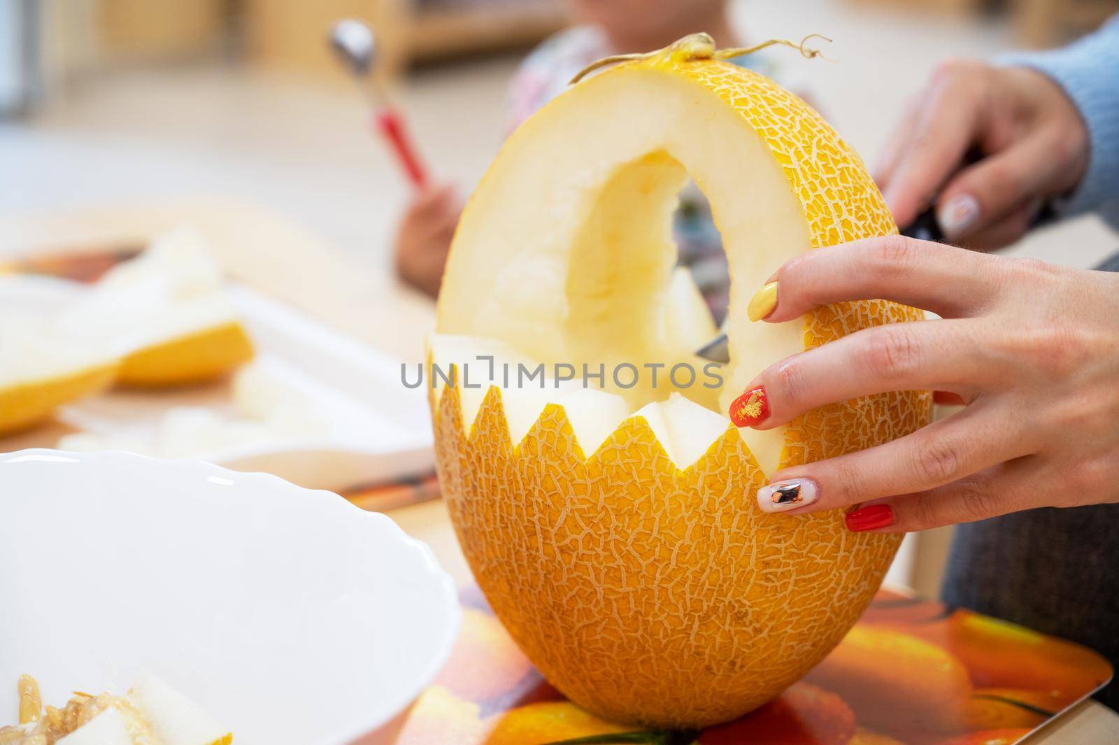 Female hands cutting pumpkin to halloween in kindergarten