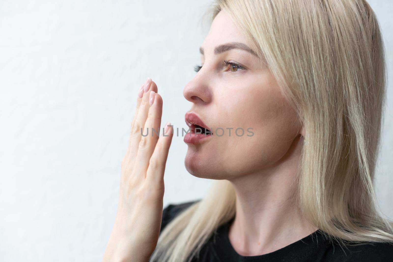 young woman checking her breath with her hand.