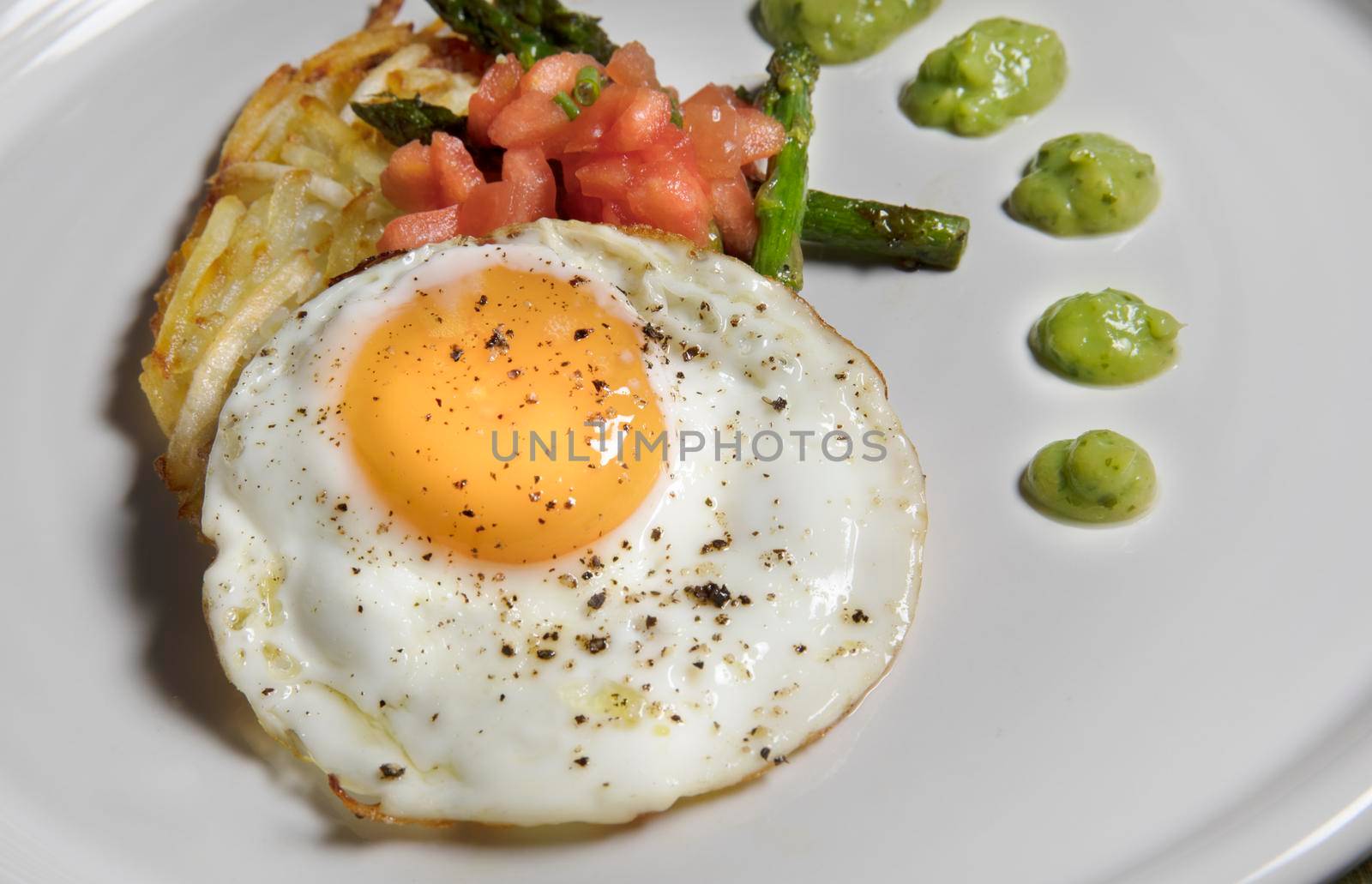 Fried egg with hashbrowns, asparagus, tomatoes and avocado sauce.