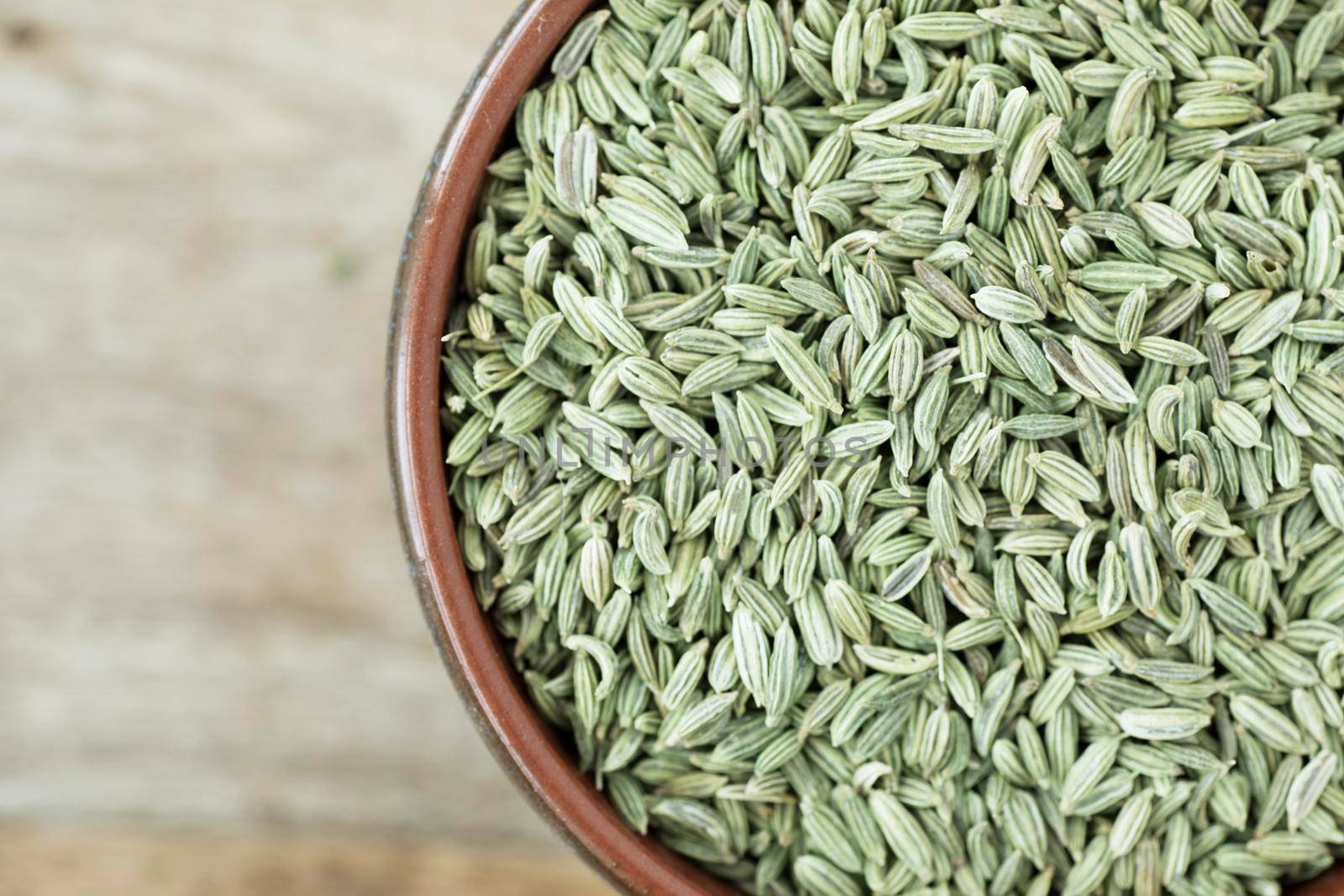 Fennel Seeds in bowl on wooden surface